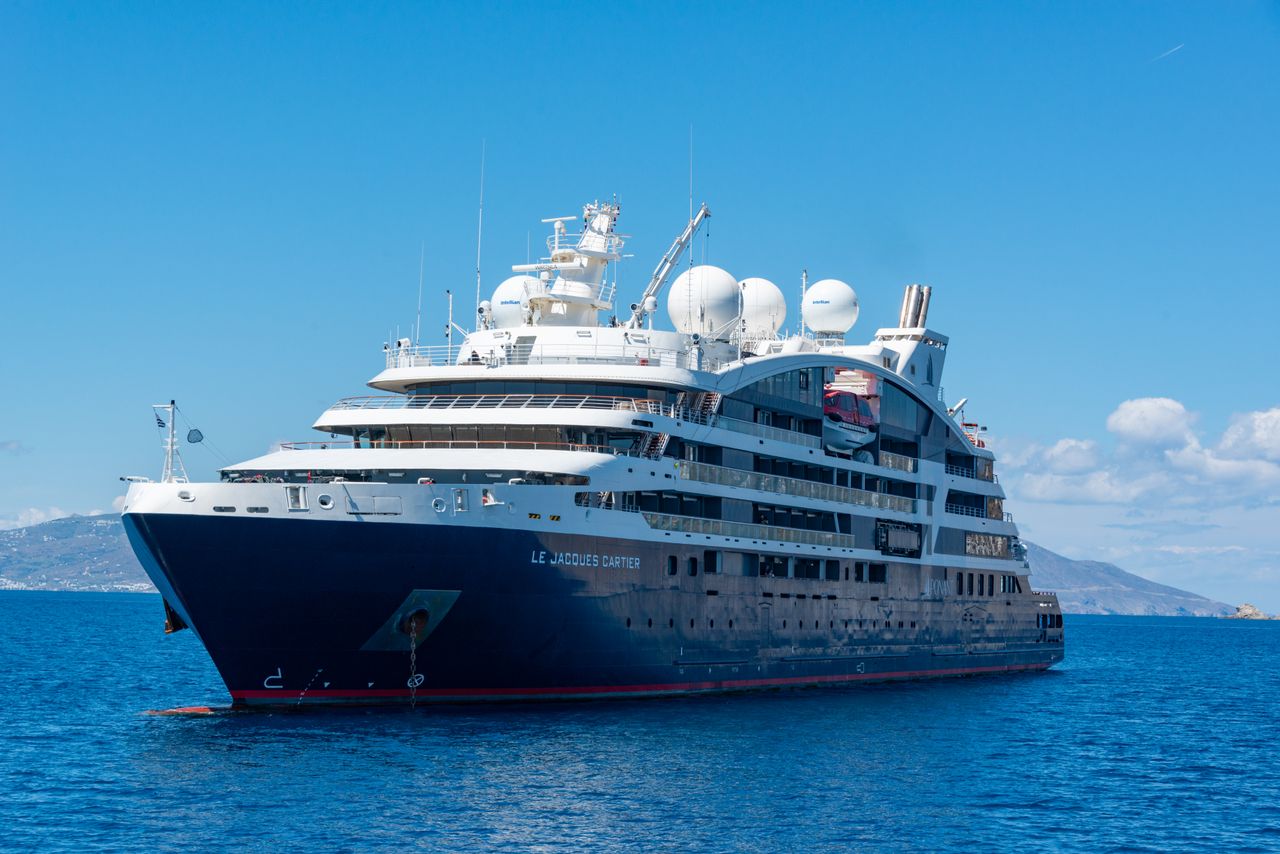 services-01 A luxury cruise ship sailing on open blue waters under a clear sky.